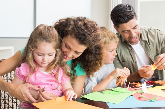 Cheerful family doing arts and crafts together at the table at h