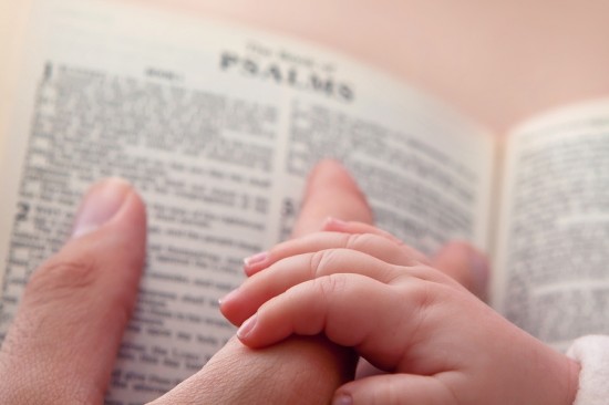 Baby Holding Dad's Finger On Bible